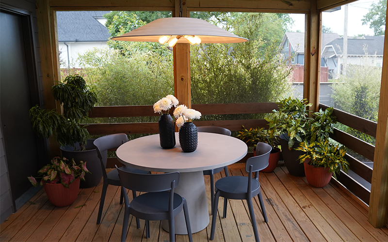 table and chairs in screened in porch with bamboo on outside of porch and potted plants on inside