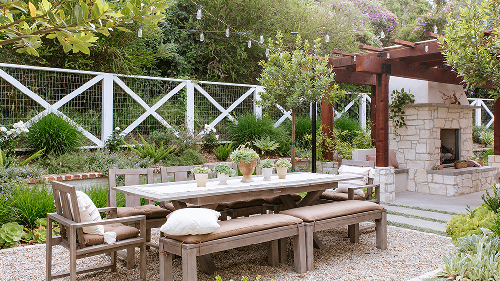 Backyard with patio furniture, a brick fireplace, and plants including grasses, foxtail ferns, and lambs ear. 