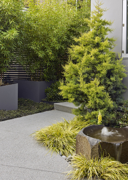 small garden entryway with fountain and lush green landscape