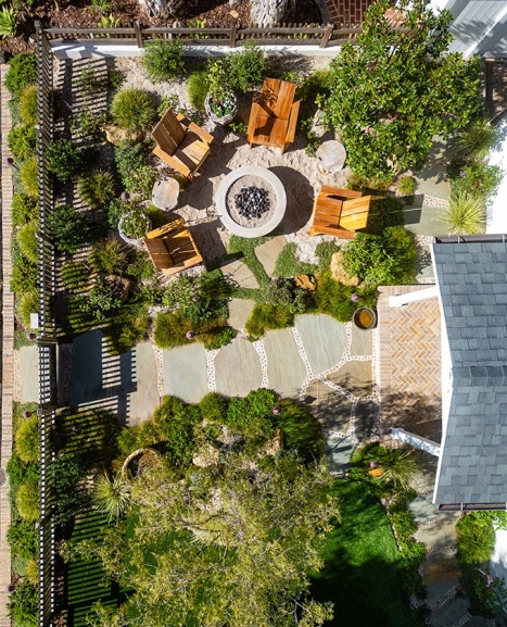 birds eye view of front yard, with fire pit and seating area at the top, a pathway through the middle, and a turf lawn on the bottom