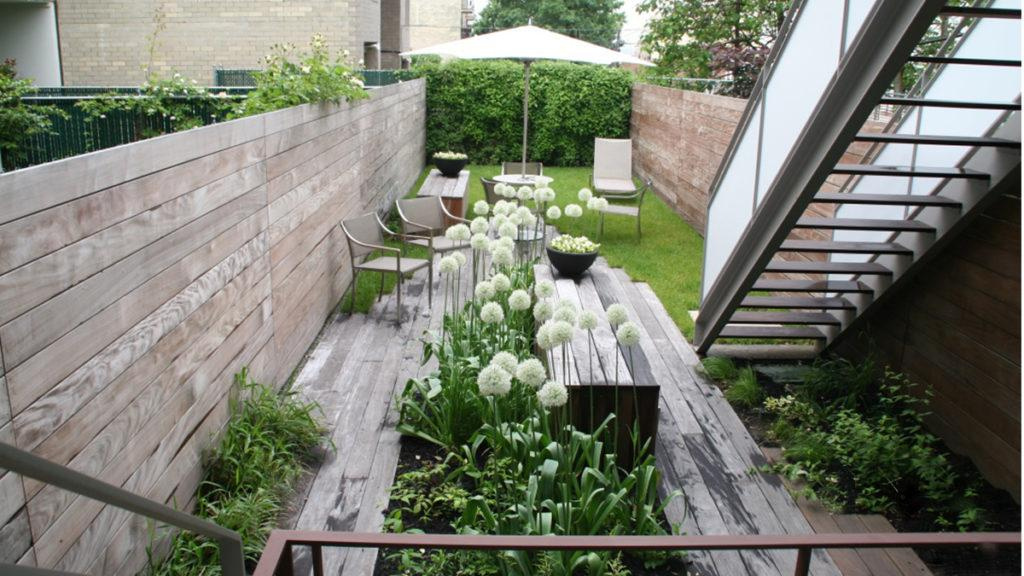 Tiny, urban backyard filled with taller grasses (feather reed and switchgrass) and perennials (white catmint and sea holly).