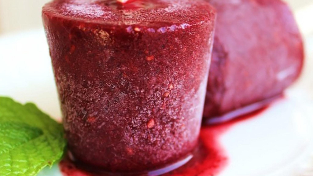 Close-up of two maroon blueberry popsicles on a counter.