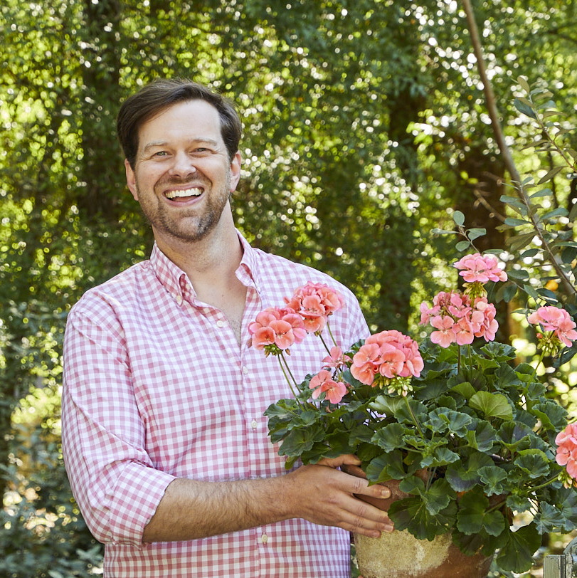 Designer James Farmer holding potted geraniums