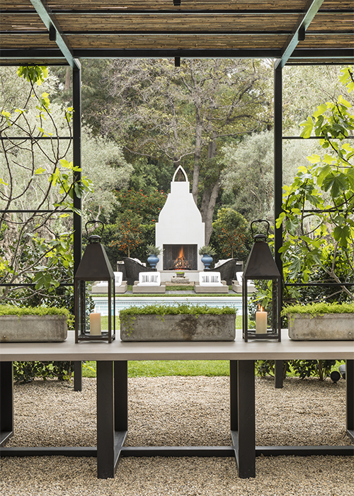 view of outdoor fireplace over table and through trellis